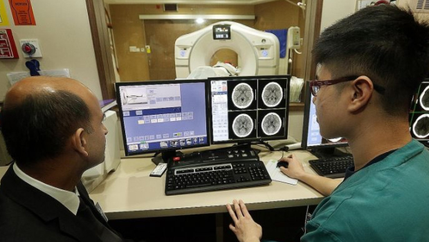  ​​Consultant Jai Rao and radiographer Douglas Tien from the National Neuroscience Institute discussing a case as a patient undergoes a computed tomography brain scan. The institute and Nanyang Technological University are in a tie-up that will see medical practitioners and engineers working together through annual fellowships and student attachment programmes.  ST PHOTO LAU FOOK KONG
